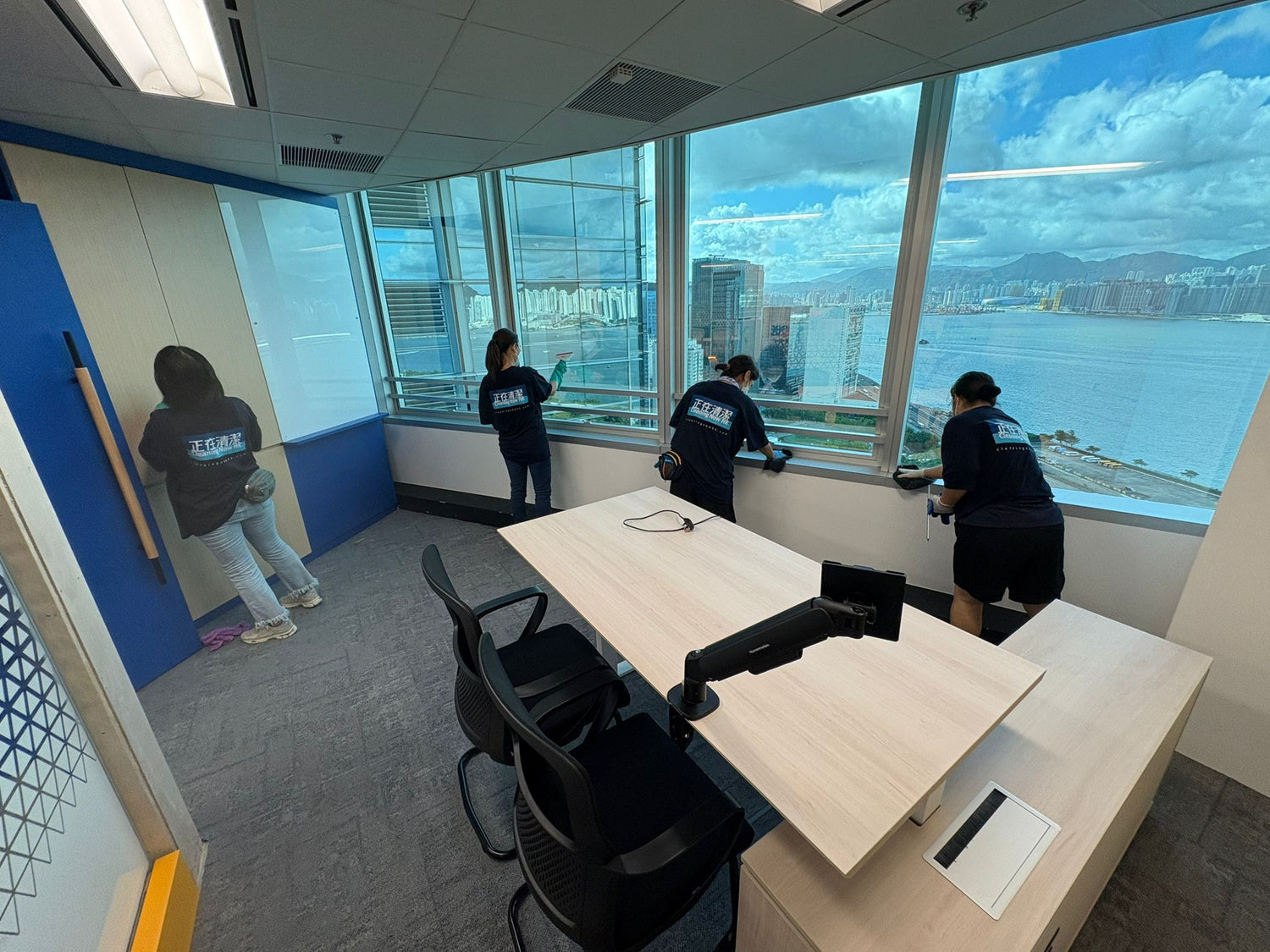 People working in a modern office with large windows overlooking a cityscape.
